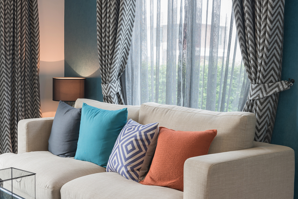 Colorful pillows on modern sofa with custom drapes